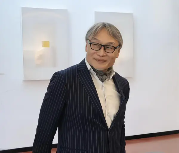 Portrait of James Liu, Founder and CEO of W by Wellness, smiling in a navy pinstripe suit in a bright gallery space